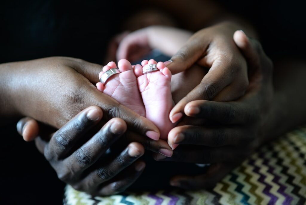 person touching babys feet with two silver colored rings